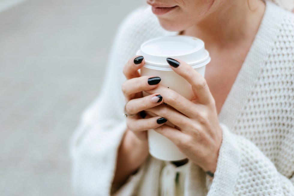 close up of womans hands with take away drink