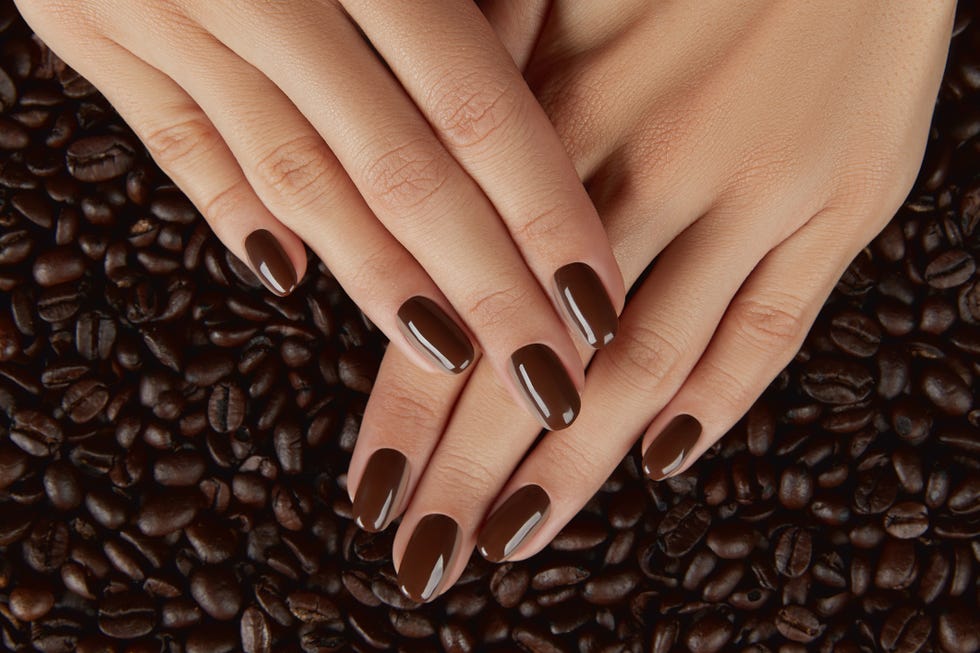 beautiful groomed womans hands with brown nail design manicure, pedicure beauty salon concept