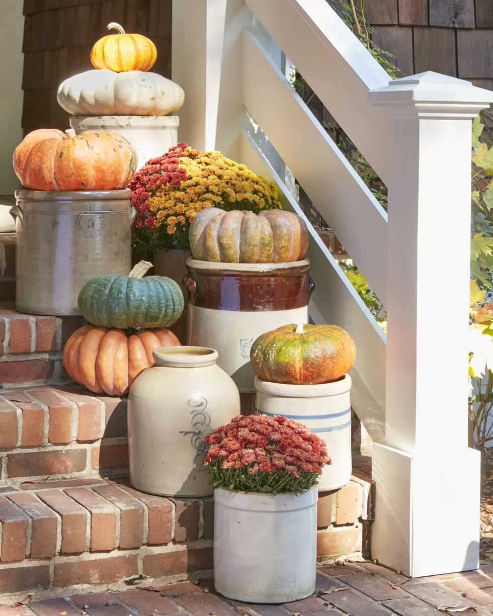 display of flat and wide pumpkins on top of an assortment of crocks staggered on a stoop or front stairs