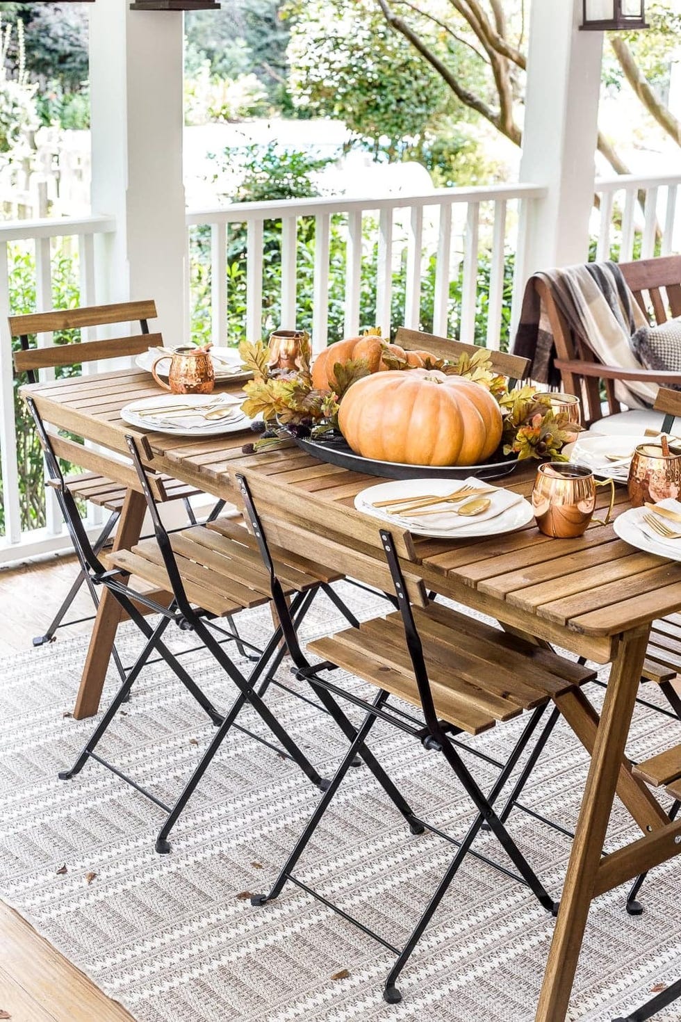 fall porch decor, copper tableware on the table on the porch with a pumpkin and chairs