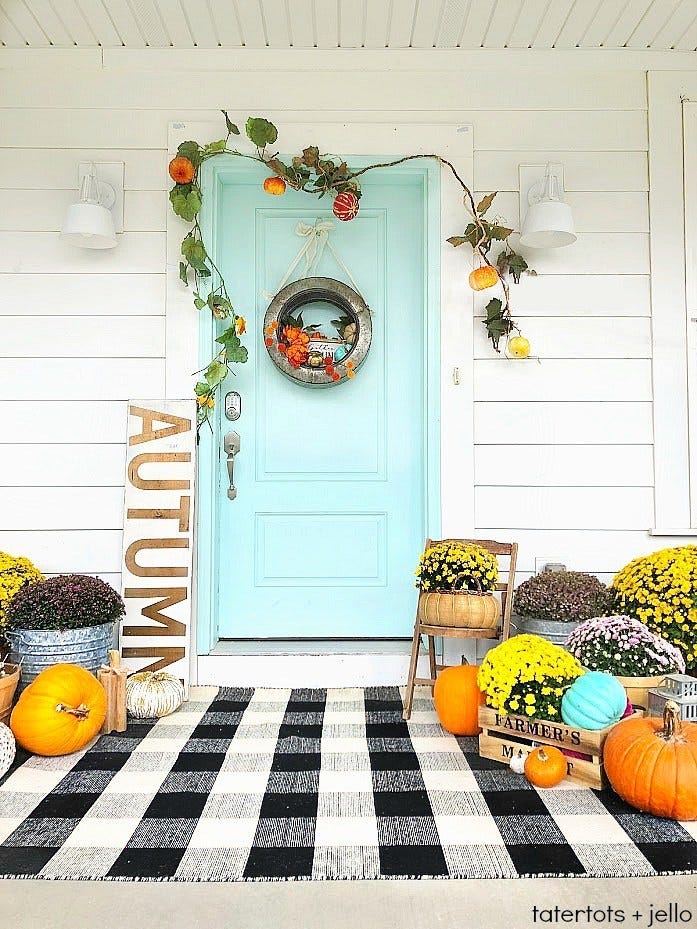 fall porch decor with black and white plaid rug, aqua door, pumpkins, mums, crates, galvanized tubs