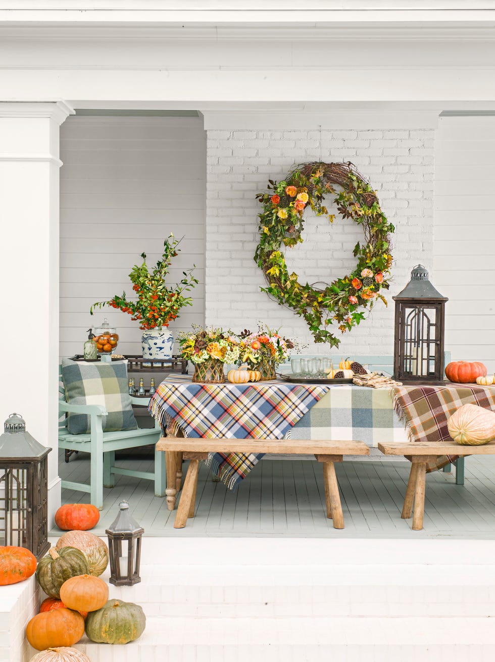 back porch with dining table covered with plaid blankets and lots of pumpkins