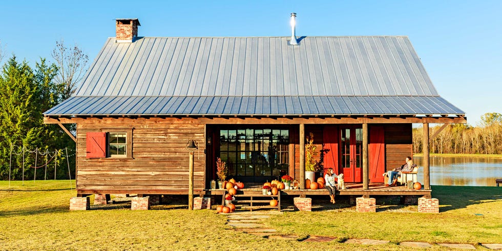 fall porch decor featuring plentiful pumpkins on the front steps and covered porch of a rustic dog trot home