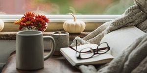 fall reading nook with blanket candle mug and white pumpkin