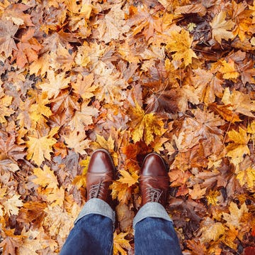 a person's feet in brown leather boots on a pile of leaves