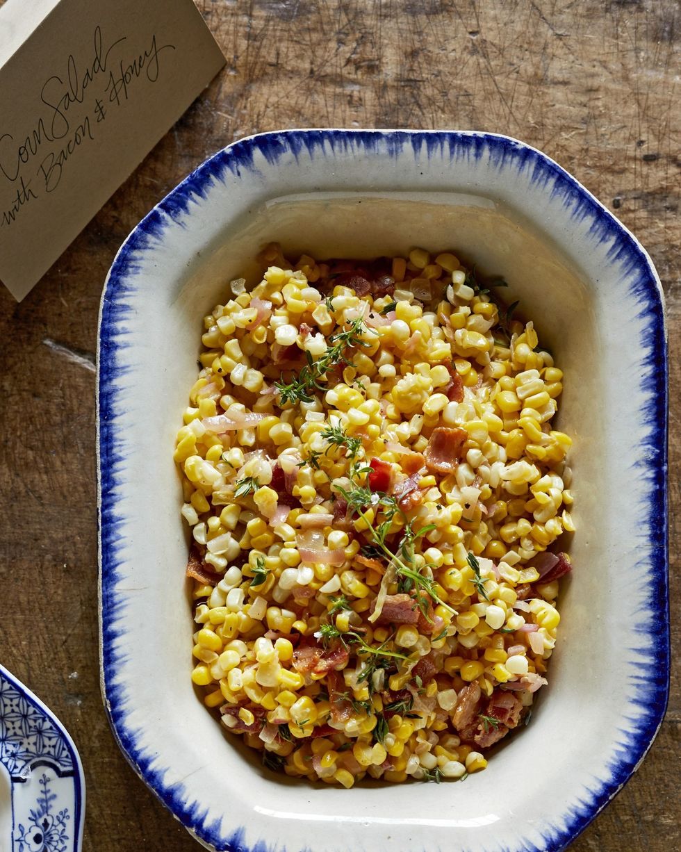 corn salad with bacon and honey in a white serving bowl with blue trim