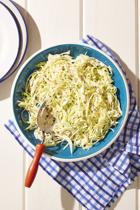 toasted seed coleslaw in a blue bowl with a serving spoon