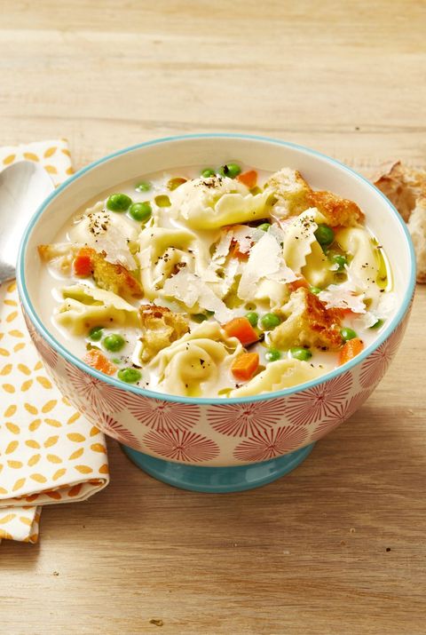 creamy tortellini soup on wood surface with bread
