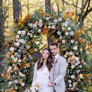 interracial couple pose at a fall wedding ceremony arch