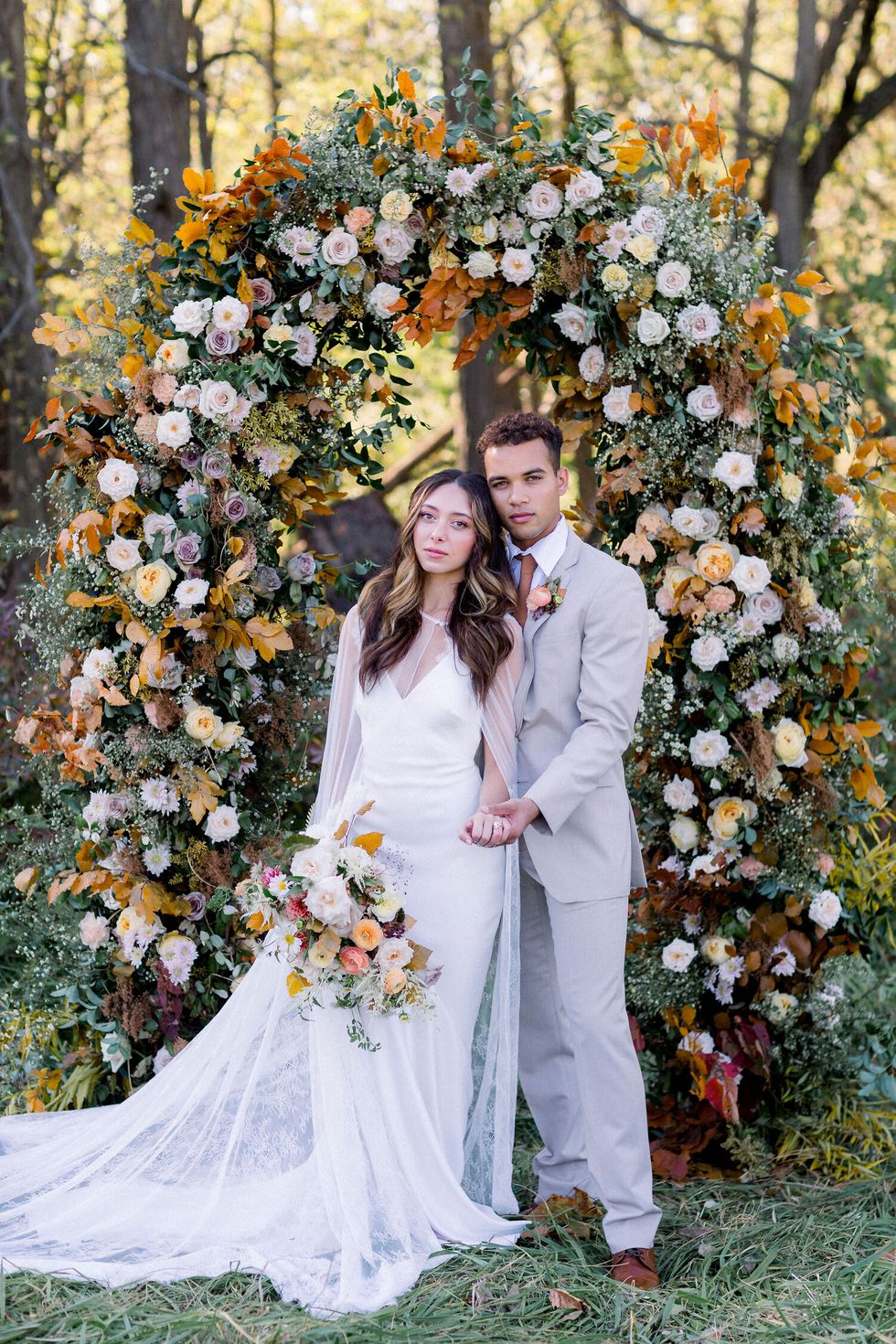 couple poses at a fall wedding ceremony arch