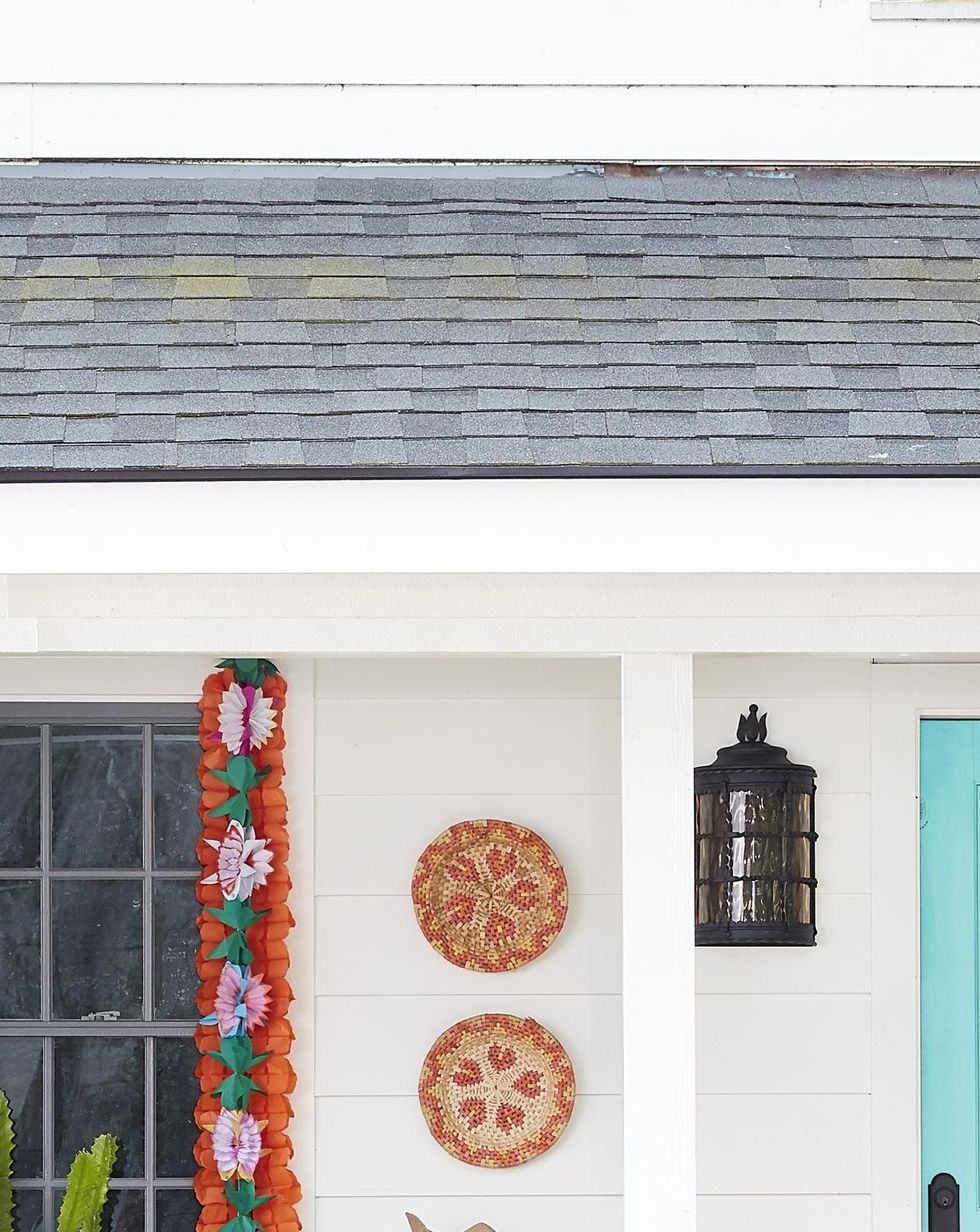 dried chili pepper wreath adorned with colorful paper flowers hanging on an aqua front door