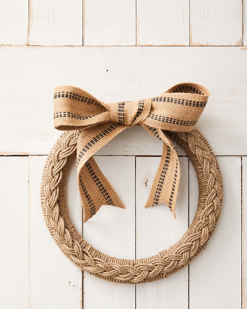 wreath form wrapped with twine with a braid made from the same material hung on a white barn door