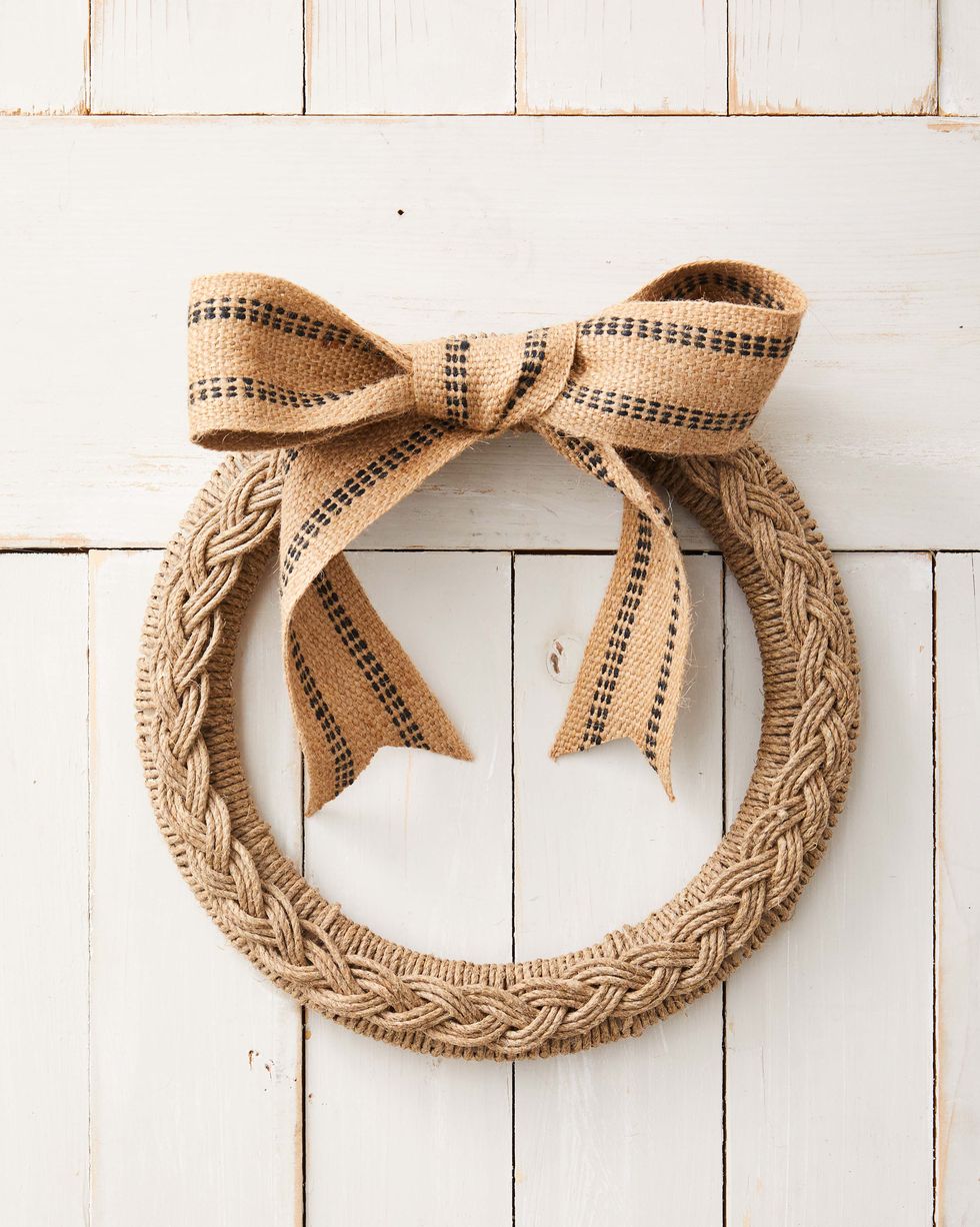 wreath form wrapped with twine with a braid made from the same material hung on a white barn door