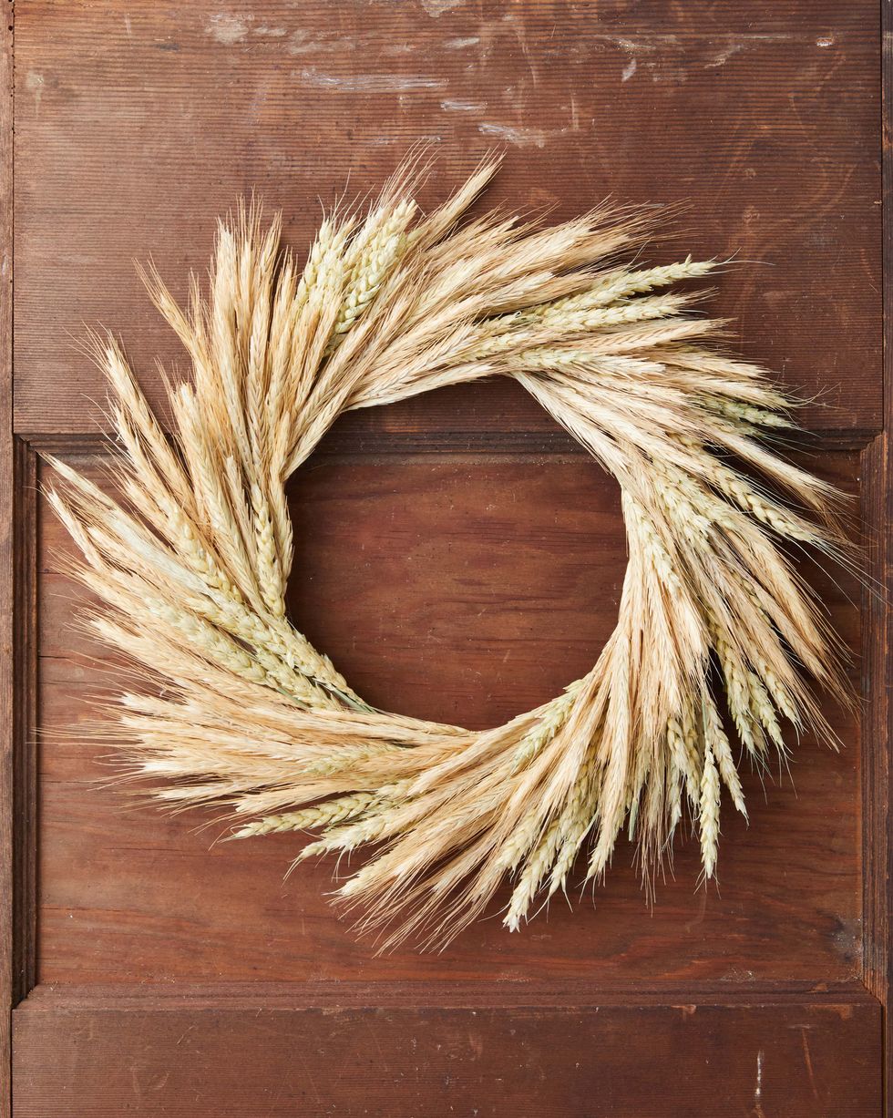 a round wreath made from two different types of what hung on a brown door
