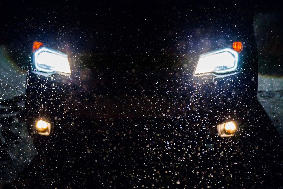 Falling snow in the headlights of the car at night