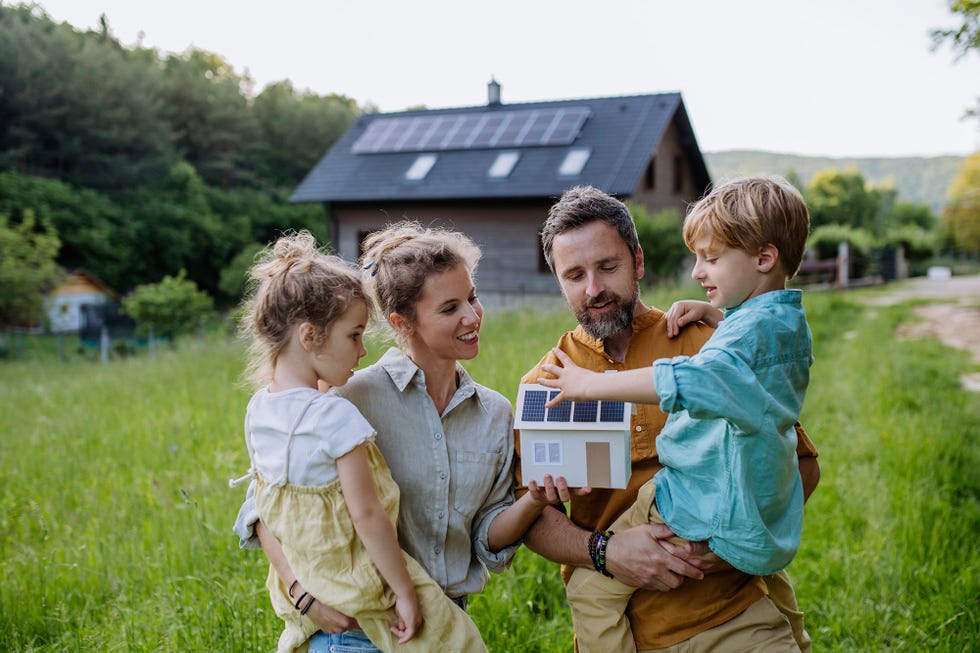 una familia feliz frente a su casa con paneles solares