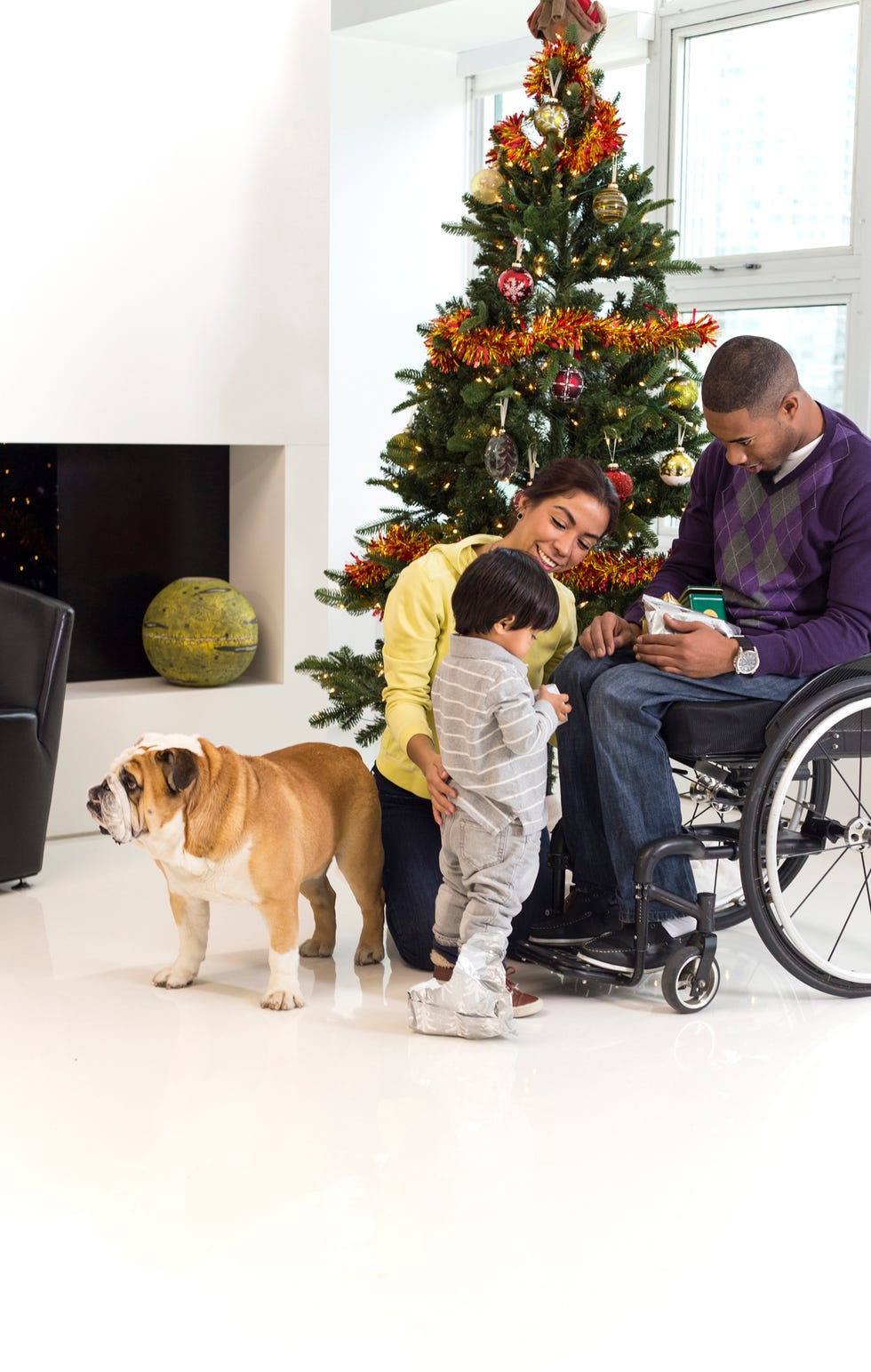 family and dog with man in wheelchair near christmas tree