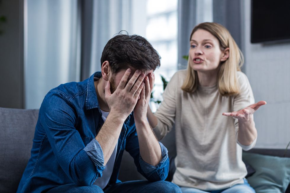 family conflict quarrel, misunderstanding the woman shouts at her husband in despaircryingrequires explanation the man listens, covering his face with his hands sitting on the couch at home