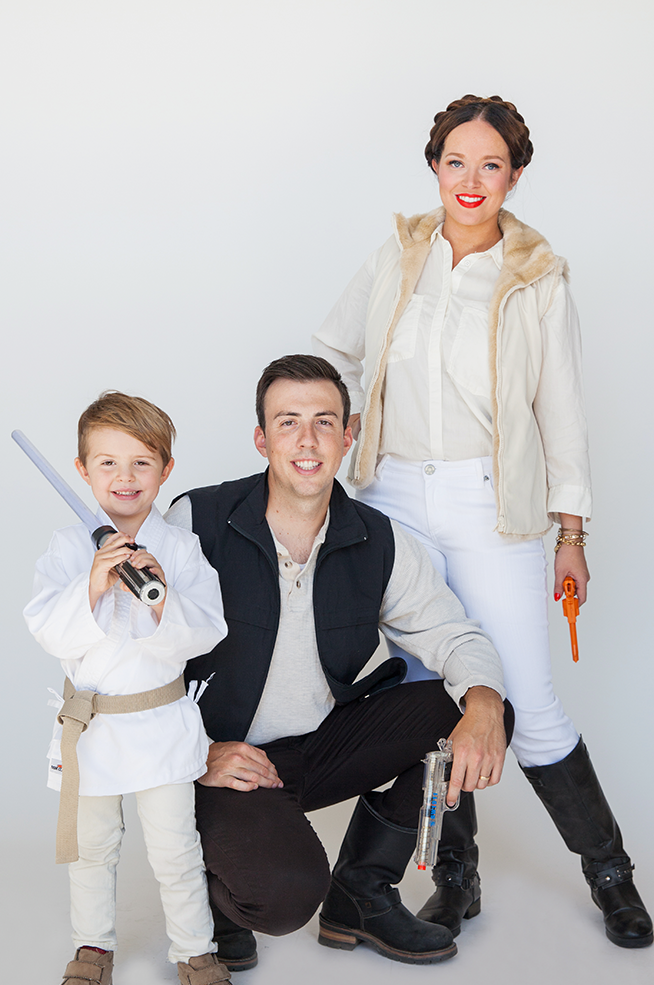 parents dressed as leia and han solo and small child as luke skywalker for a family halloween costume for 3