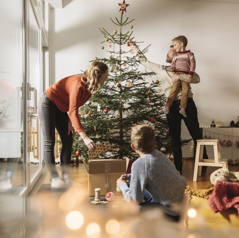 family of four decorating their christmas tree