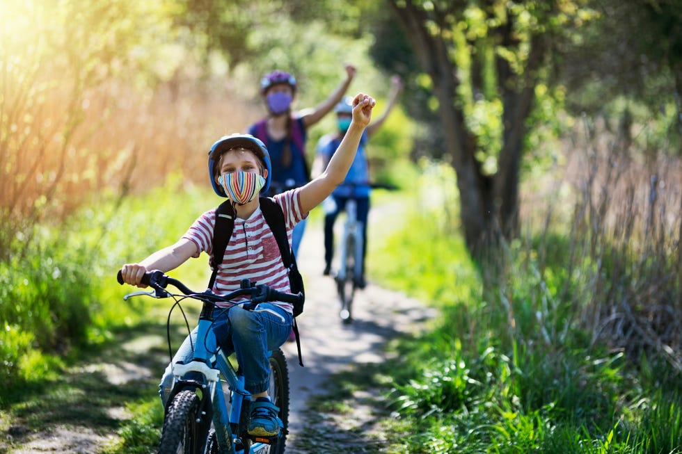 una familia, con mascarillas, monta en bicicleta por el campo