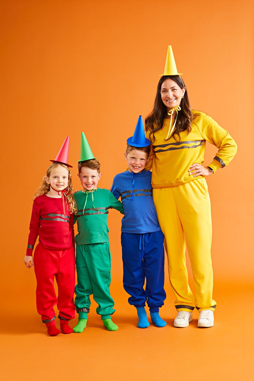 three kids and an adult dressed as different color crayons for halloween