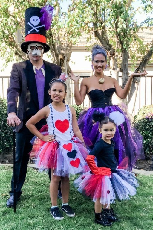 a family dressed in a disney villains family costume with dr facilier ursula the queen of hearts and cruella