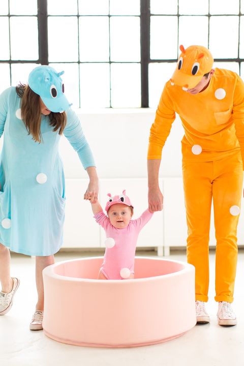 a family of two parents and a baby dressed in a hungry hungry hippos family halloween costumes