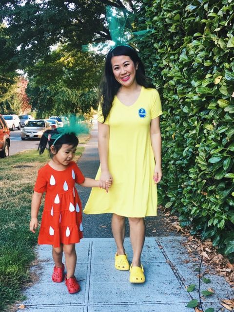 a girl dressed as a strawberry and a mom dressed as a banana in a fruit family halloween costume