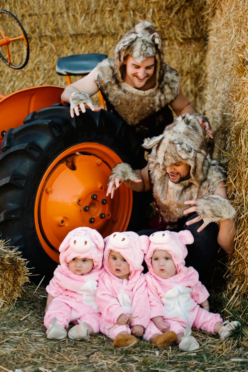 Two fathers dressed as wolves stand next to triplets dressed as piglets