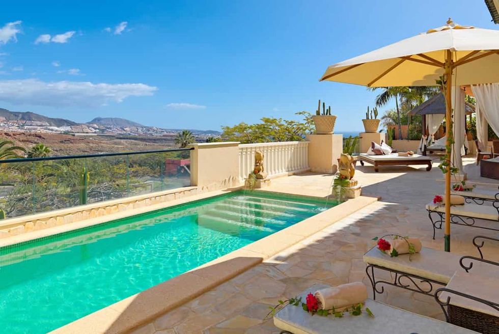 a pool with a deck and umbrellas at royal garden villas and spa