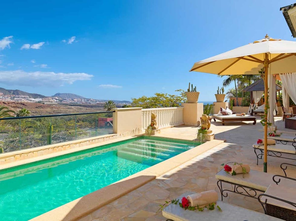 a pool with a deck and umbrellas at royal garden villas and spa
