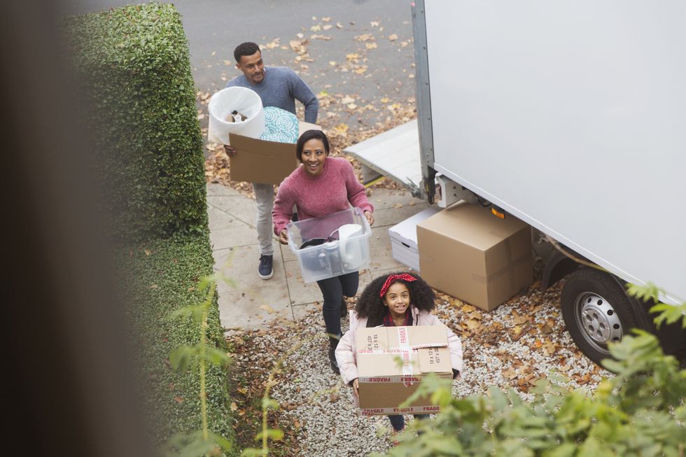 Family moving into new house, carrying boxes from moving van