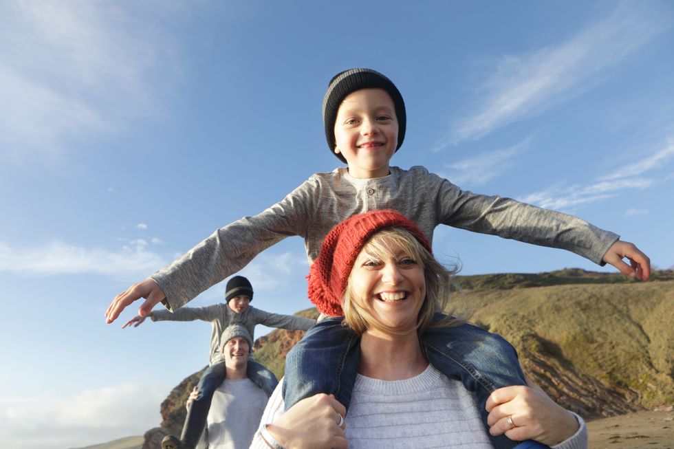 Family on beach in winter, mother giving son piggyback
