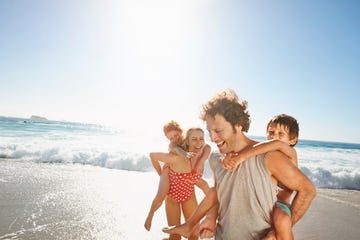 unos padres juegan en la playa con sus hijos