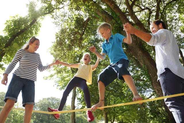 family playing on slackline in park