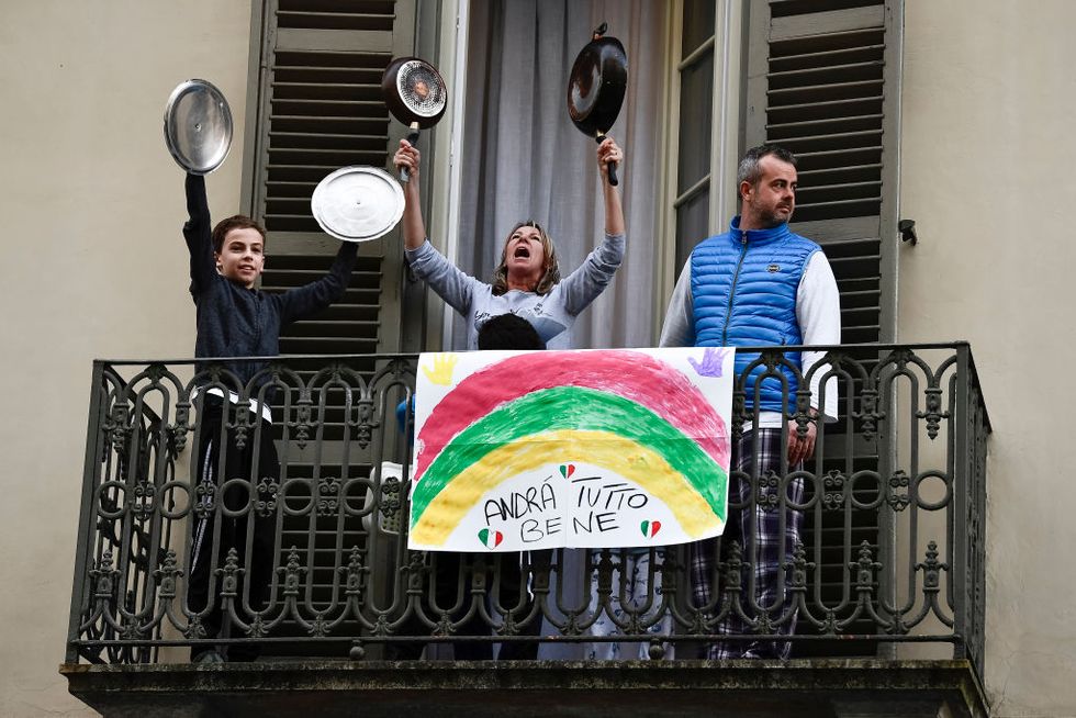 A family plays lids of pots and pans from balcony of their...