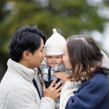 family portrait in winter public park kissing to baby
