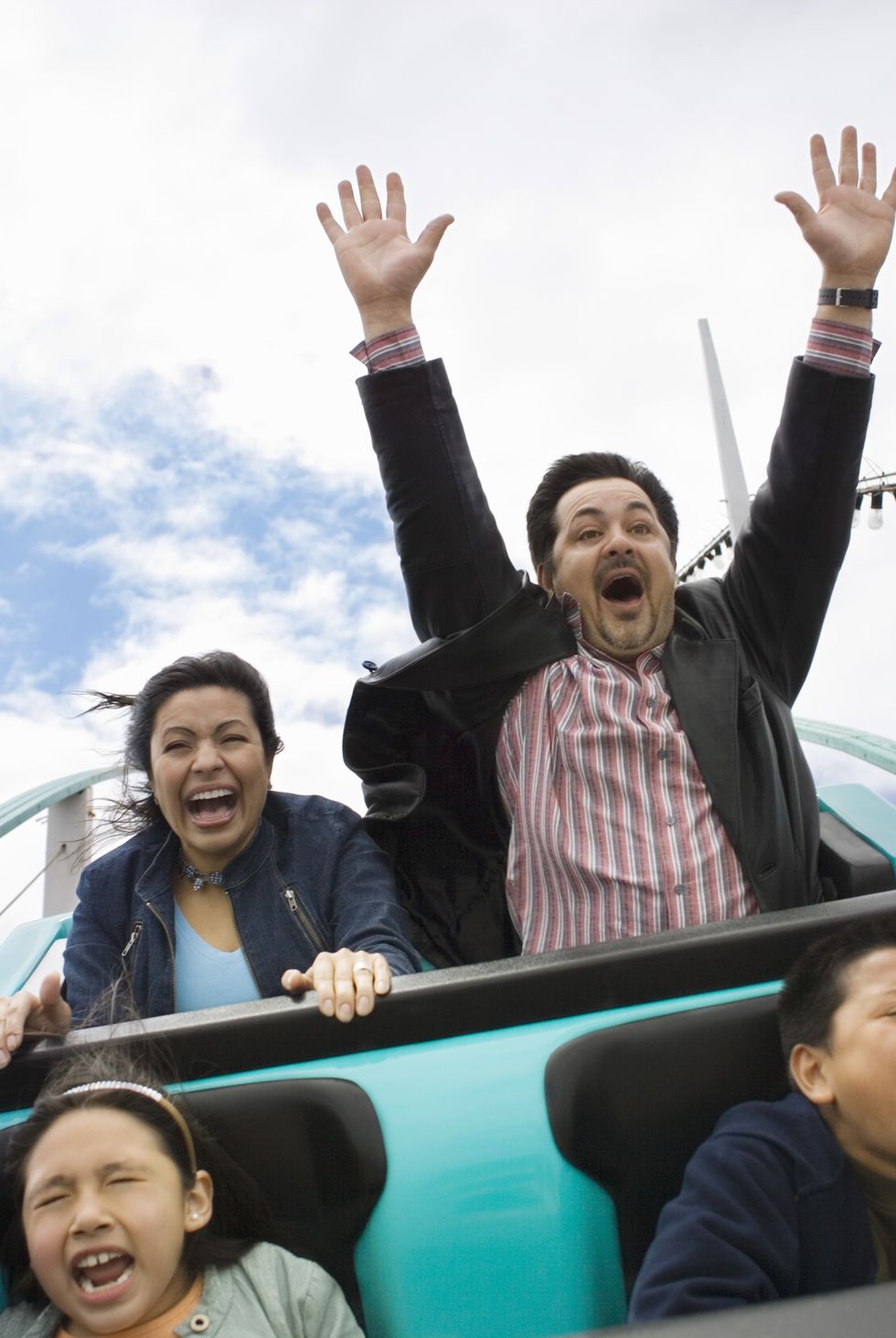 family riding rollercoaster, father with hands up in air