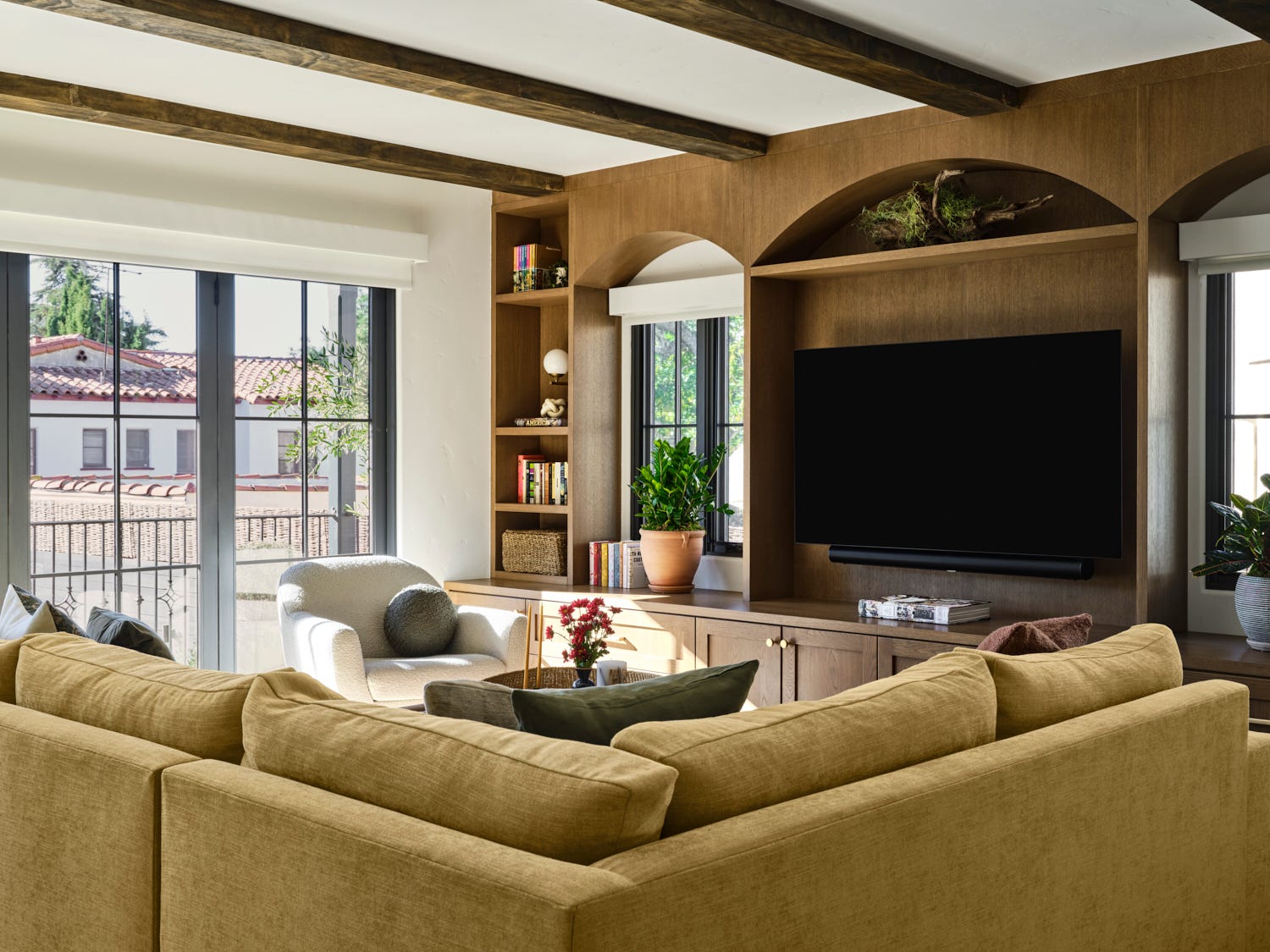 a spacious living room features a large, beige sectional sofa positioned to face a mounted flat screen television