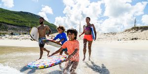 family running and splashing into sea together with body boards