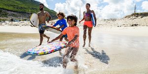 family running and splashing into sea together with body boards