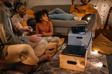 family sitting together watching movie on projector screen