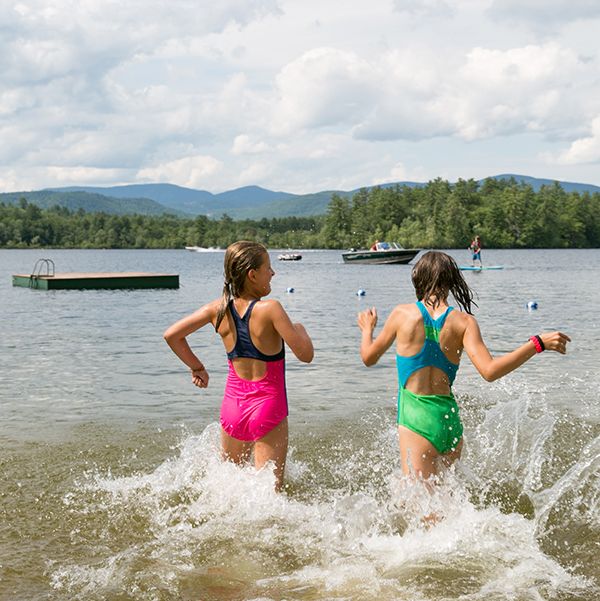 two friends frolic in a lake at the quisisana resort, a good housekeeping pick for family vacation destinations