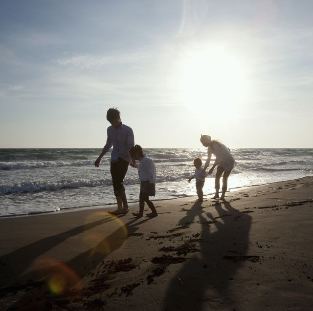 family who strolls on beach of evening