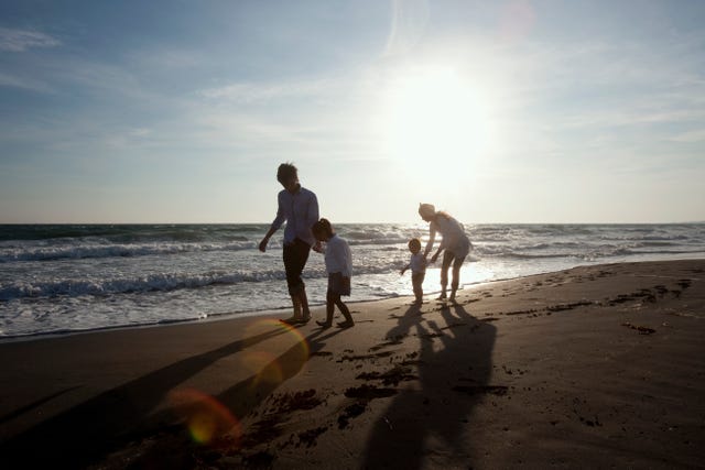 family who strolls on beach of evening