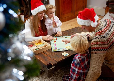 family with board game, parents in christmas hats