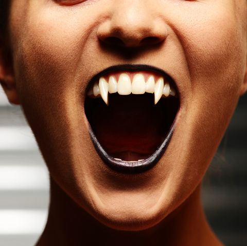 close up of a vampire womans mouth over dark background