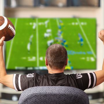 man watching football on tv while holding a football