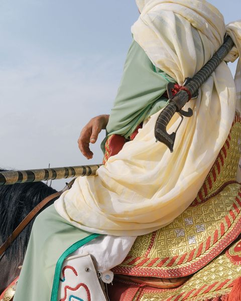 De ruiters dragen tijdens de Fantasia traditionele djellabas waarmee ze zich met meerdere lagen stof tegen het woestijnzand beschermen